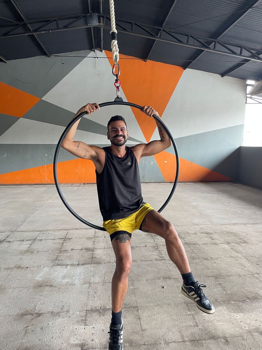 Felipe Monteiro sentado na lira acrobática, sorrindo